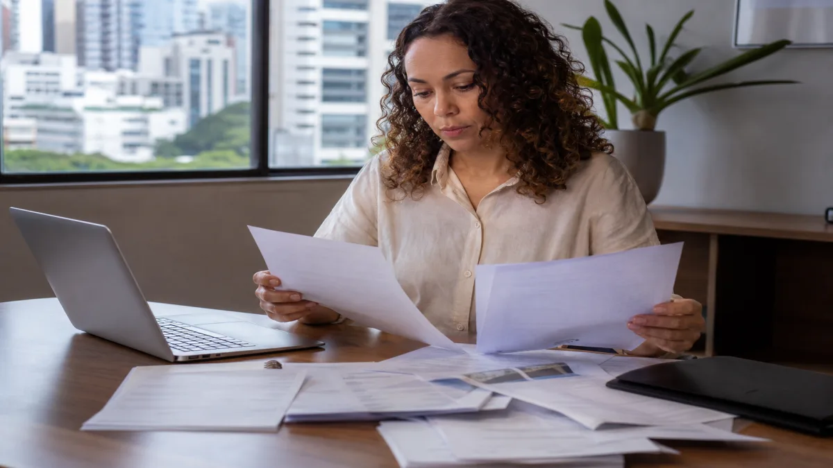 Pessoa analisando apólices de 3 vantagens de seguros residenciais em escritório com documentos na mesa.